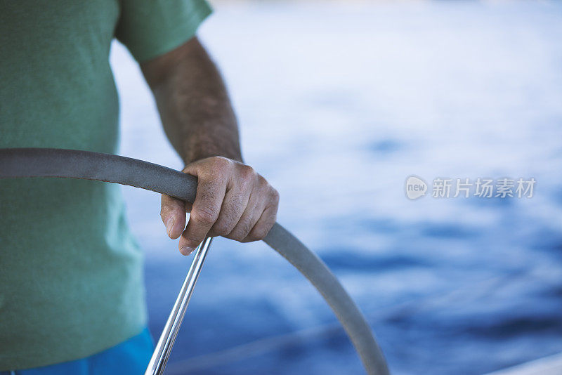 Hands of man on boat's wheel, sailing